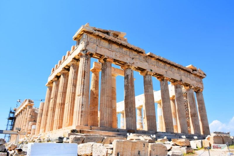The Parthenon temple on the Acropolis in Athens, Greece, featuring ancient marble columns against a clear blue sky, a top destination for travelers.