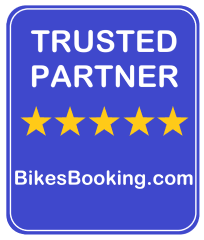Ένα μπλε σήμα με το κείμενο Trusted Partner και πέντε κίτρινα αστέρια, που υποδηλώνει συνεργασία με την πλατφόρμα ενοικίασης μοτοσυκλετών BikesBooking.com. gstraveler